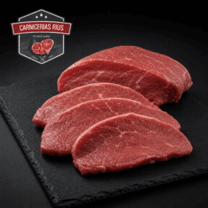 Carne roja en lonchas sobre pizarra negra.