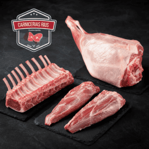 Cortes de cordero frescos: carré de cordero, pierna entera y solomillos sobre pizarras negras, productos de calidad de Carnicería Rius en Nou Barris, Barcelona 