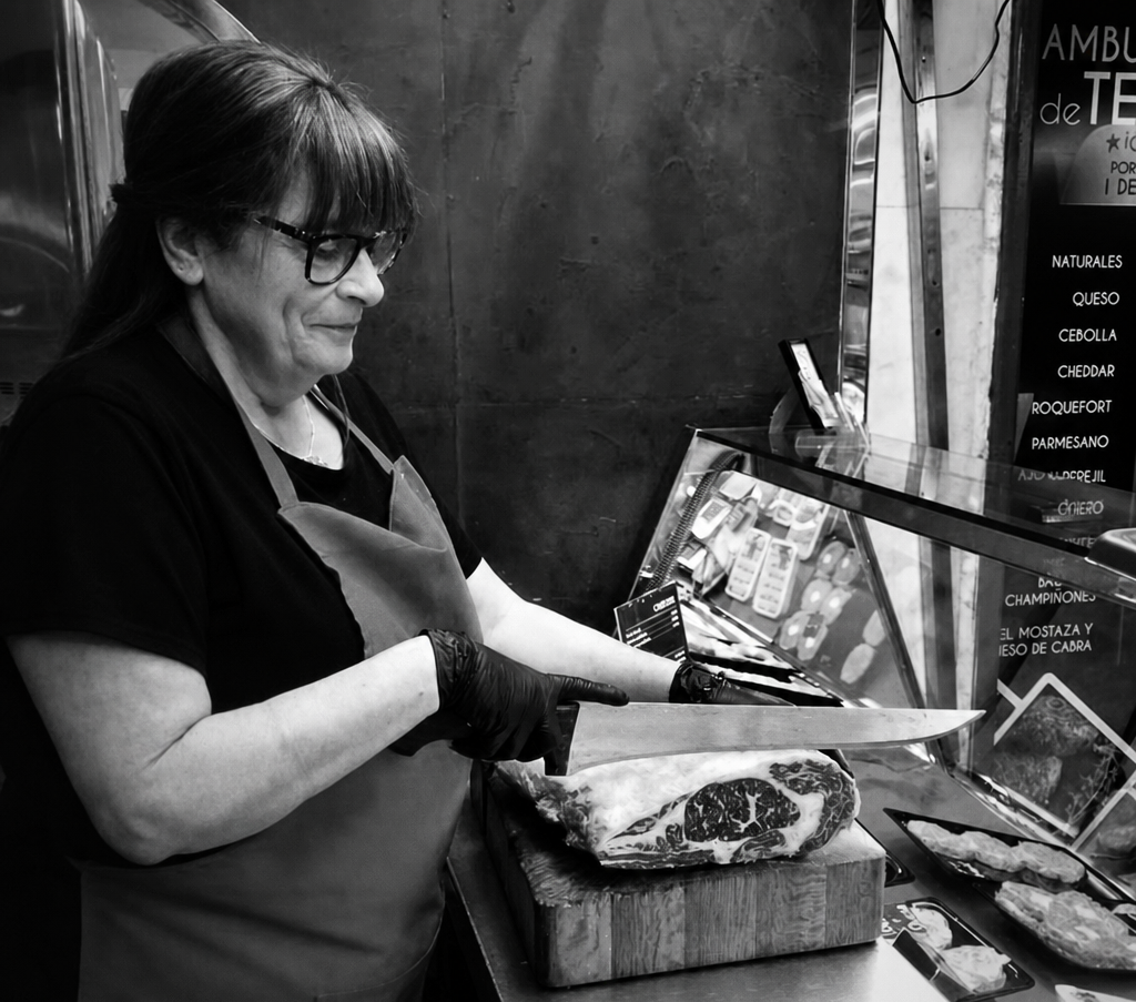 Mujer cortando jamón en una tienda.